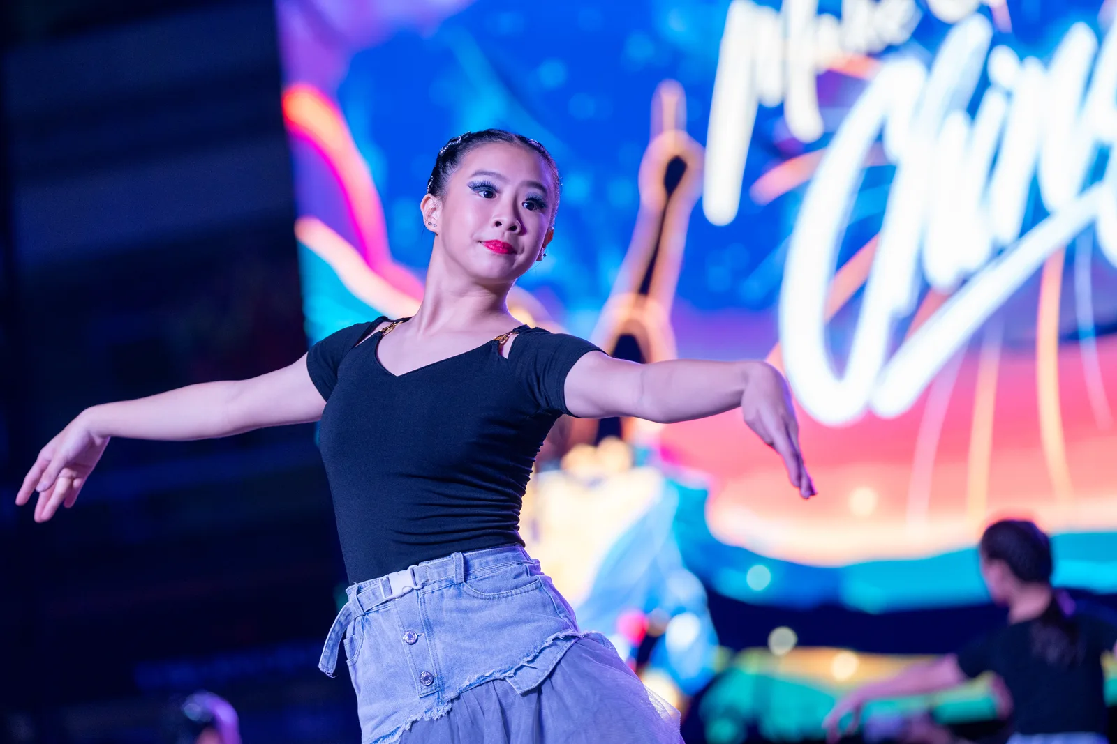 Dancer mid-movement under dramatic stage lighting against a deep blue backdrop