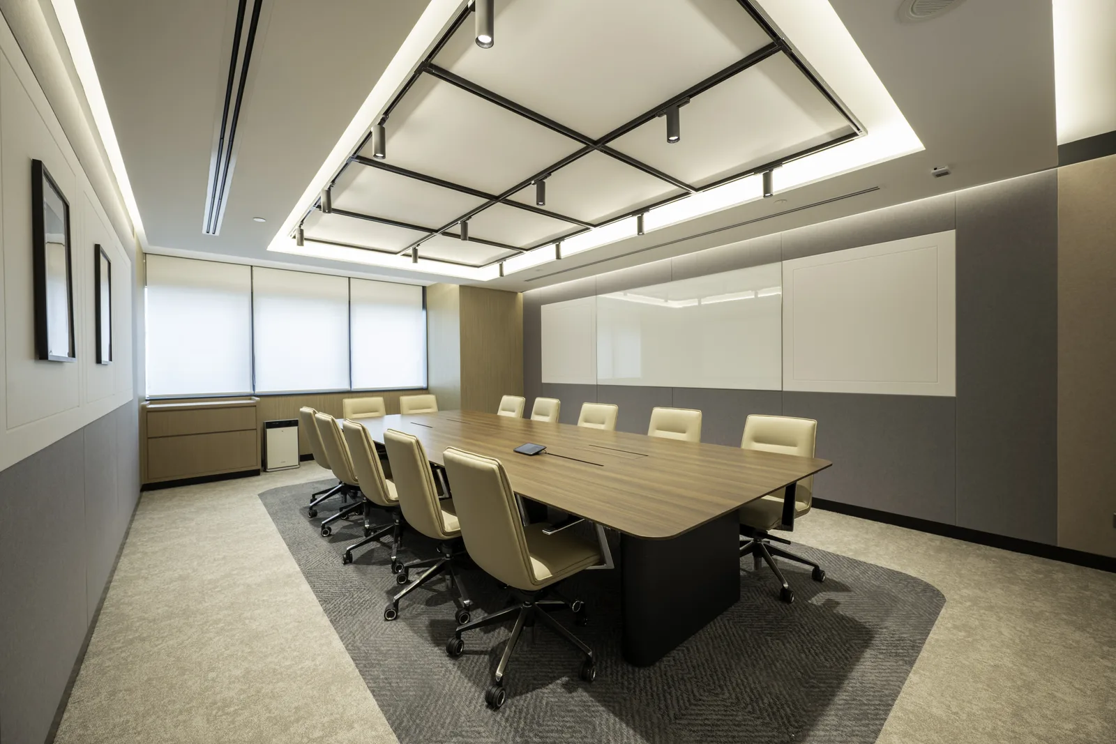 Empty modern boardroom with a long table and architectural ceiling lighting