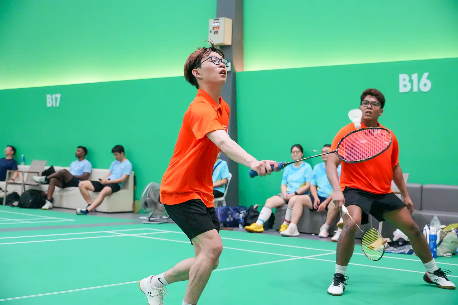Badminton players mid-rally during a corporate sports tournament