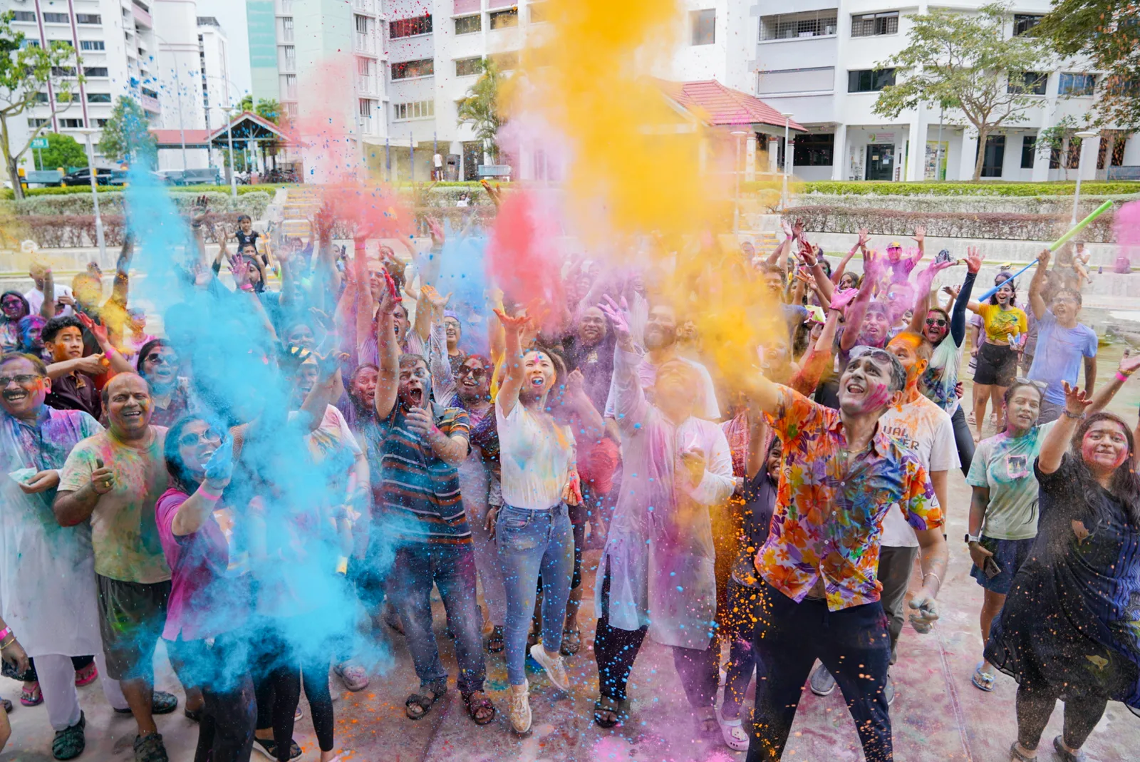 Crowd celebrating in a burst of blue and orange colour powder at a Holi festival in Singapore