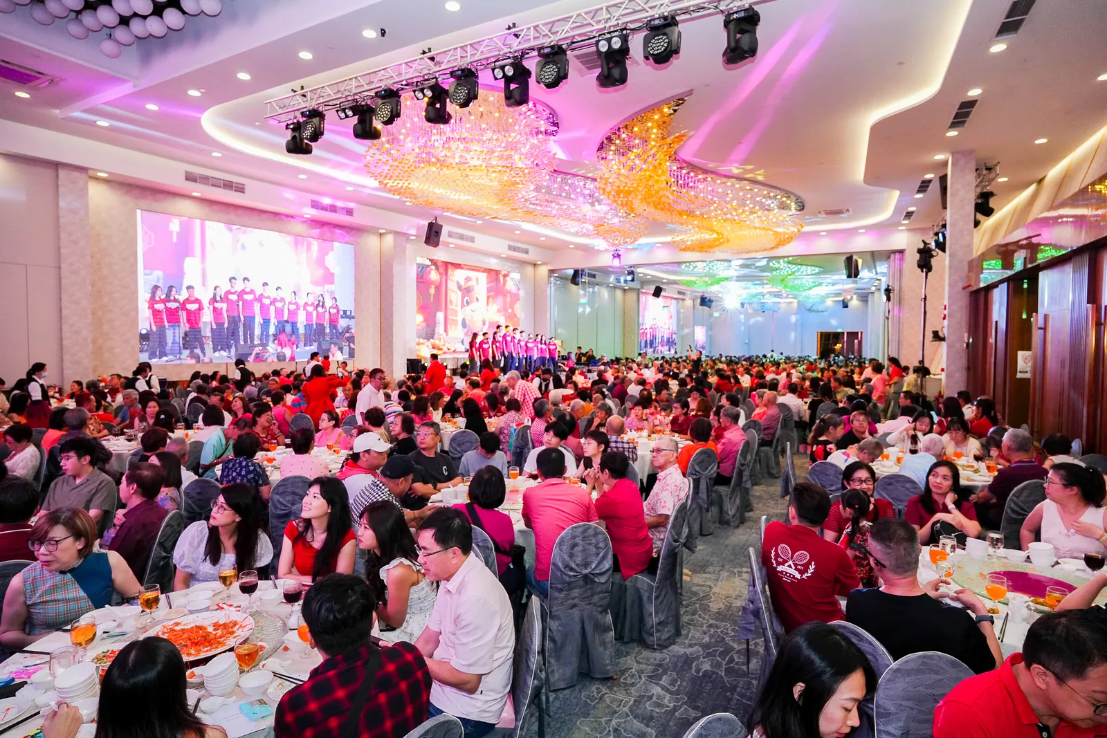 Wide view of a chandelier ballroom with a full house of banquet tables during a gala dinner