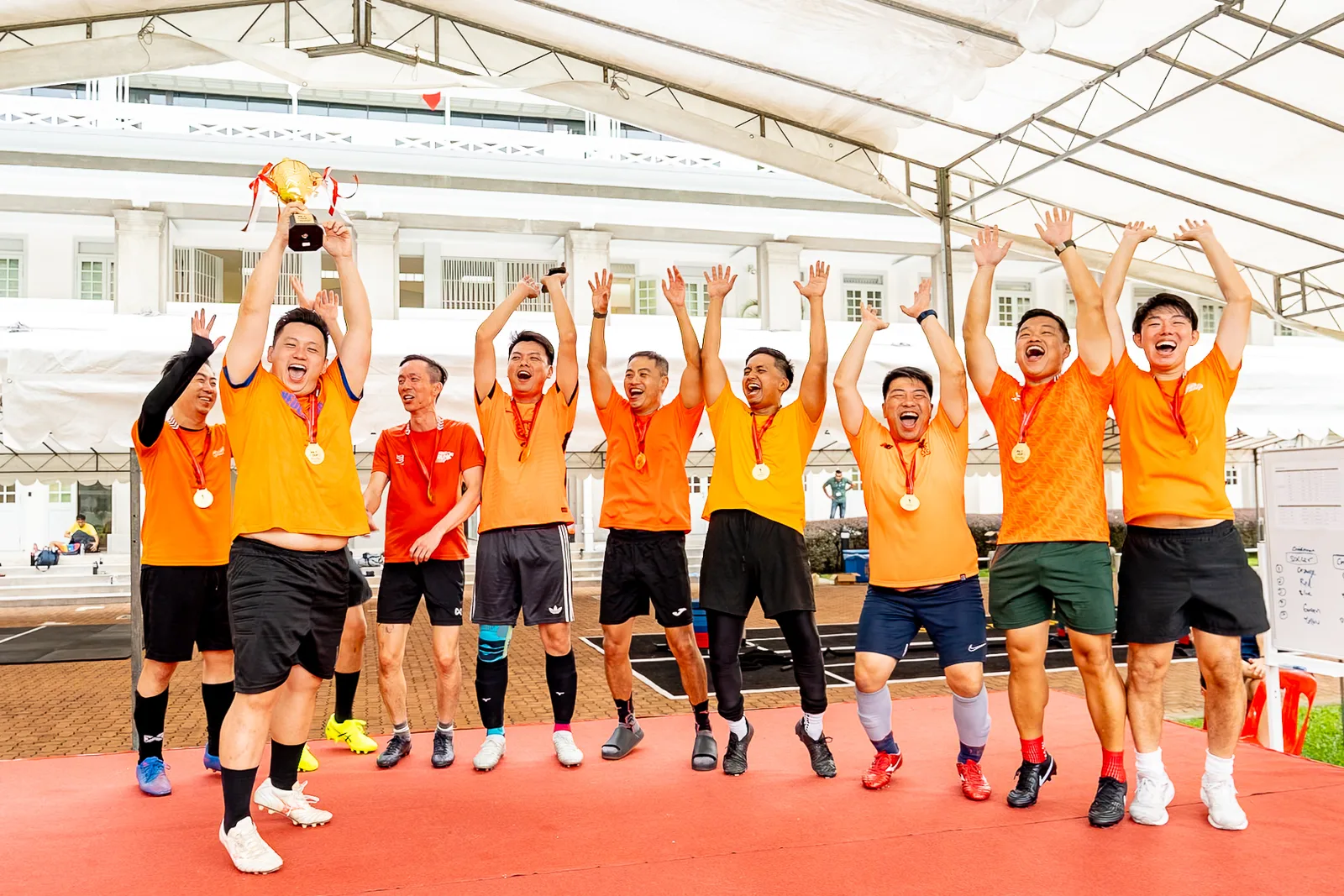 Team celebrating with arms raised after a company sports event in Singapore