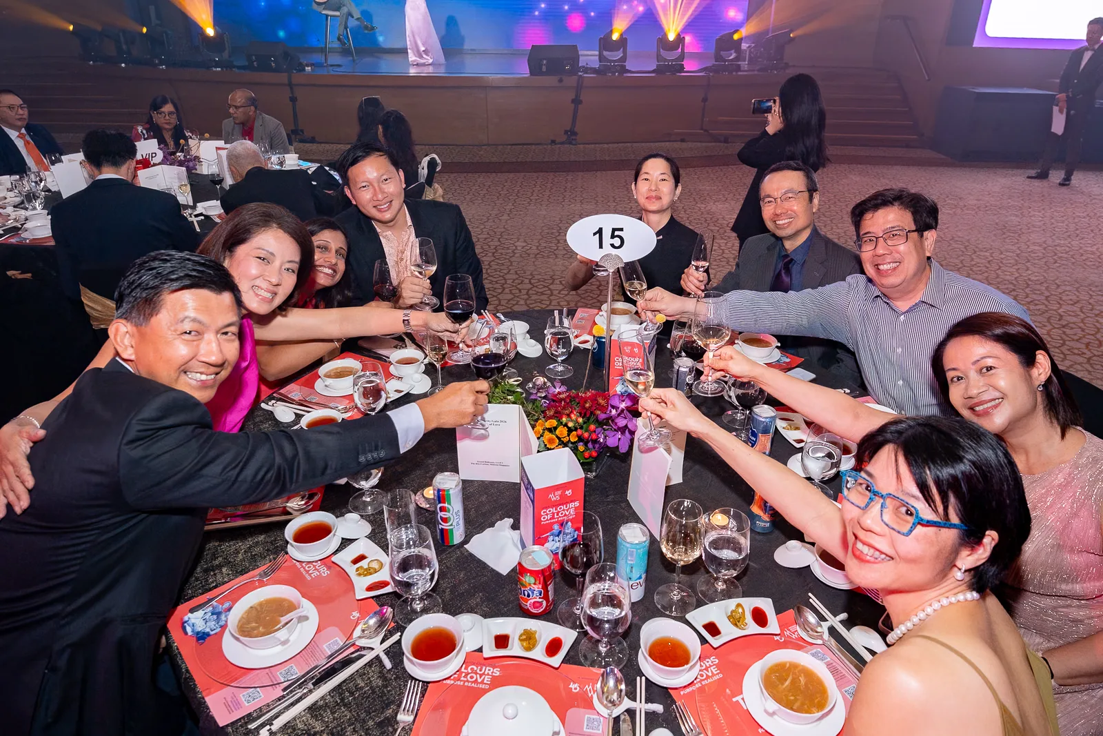 Guests raising glasses and laughing around a table at a corporate gala dinner