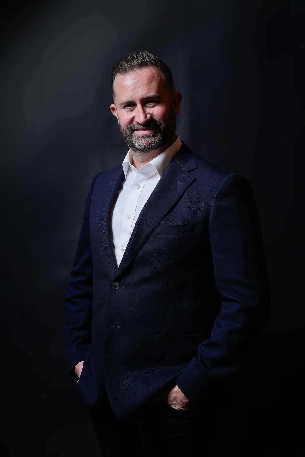 Low-key studio portrait of a professional against a dark background with soft rim lighting