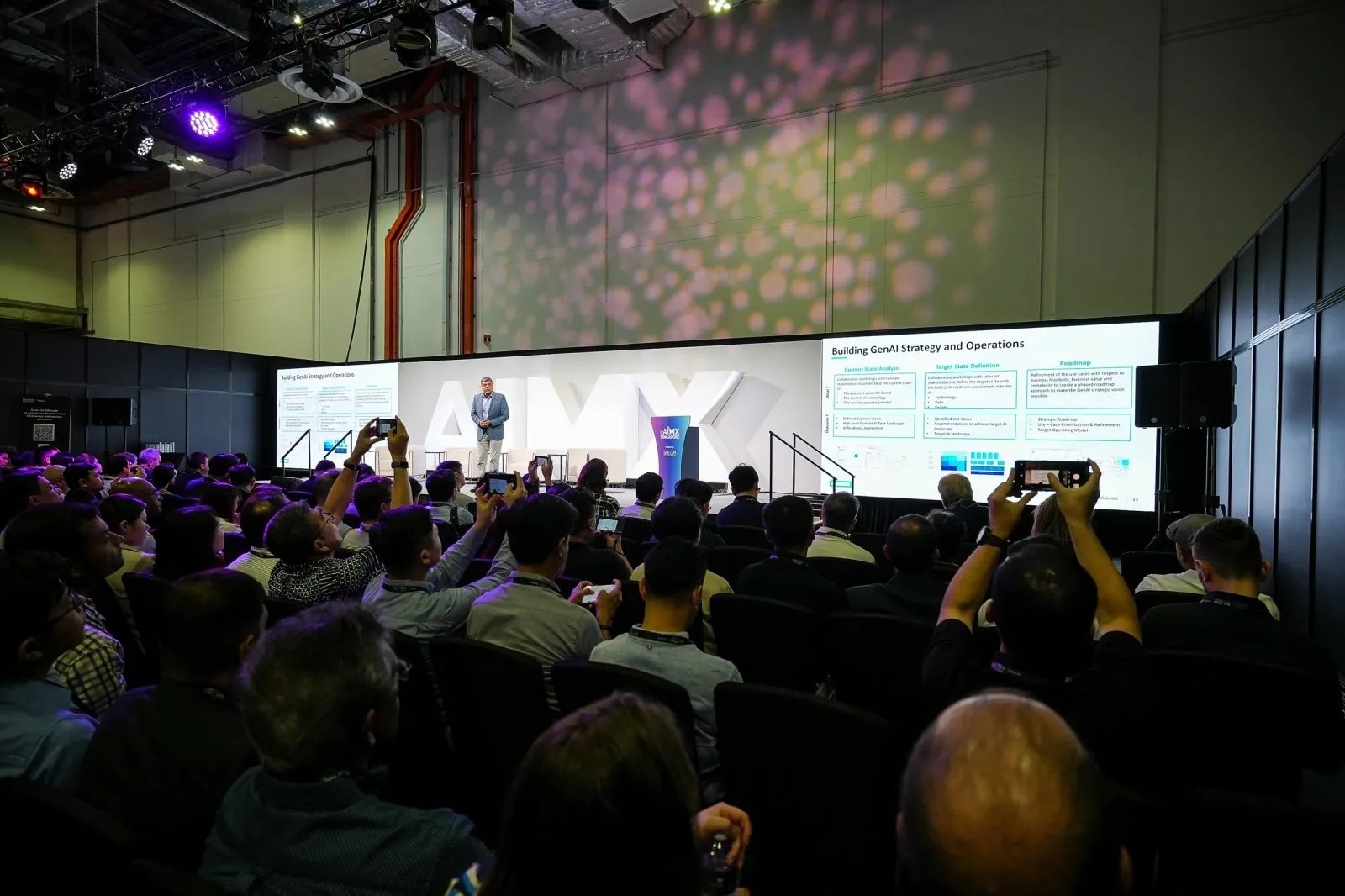Conference audience watching a presentation across two large LED screens — RS Photography
