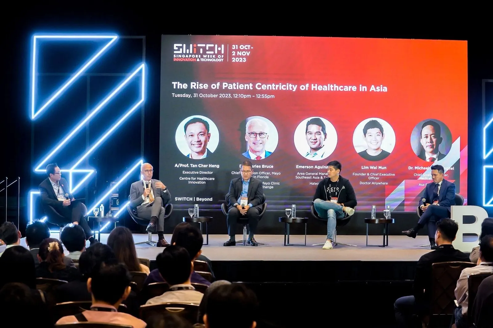 Healthcare panel on a conference stage with a full LED backdrop and seated audience — RS Photography