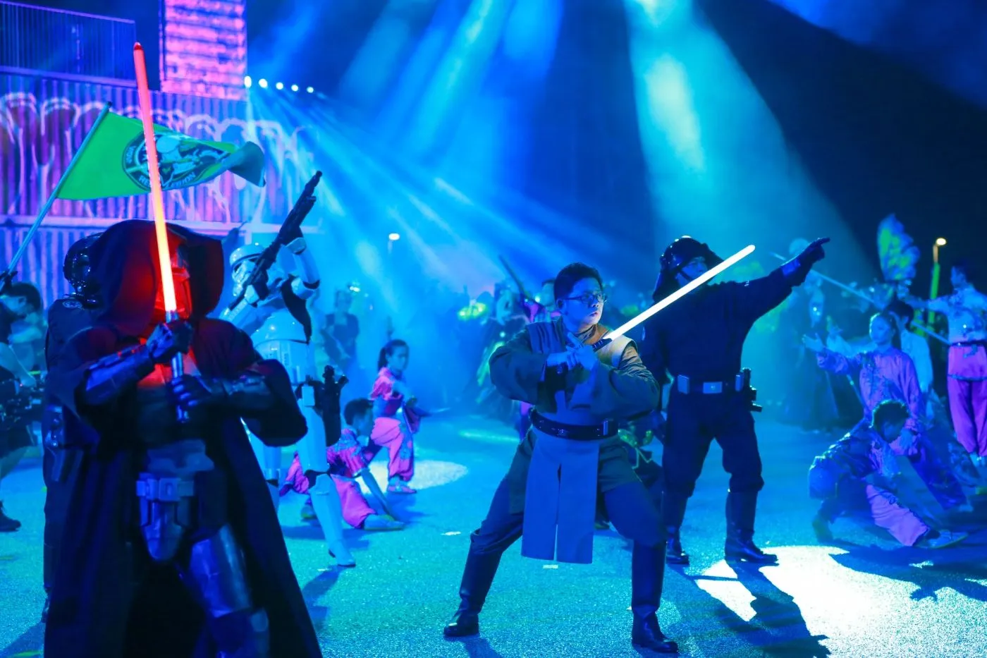 Costumed performers duelling with lightsabers under blue light