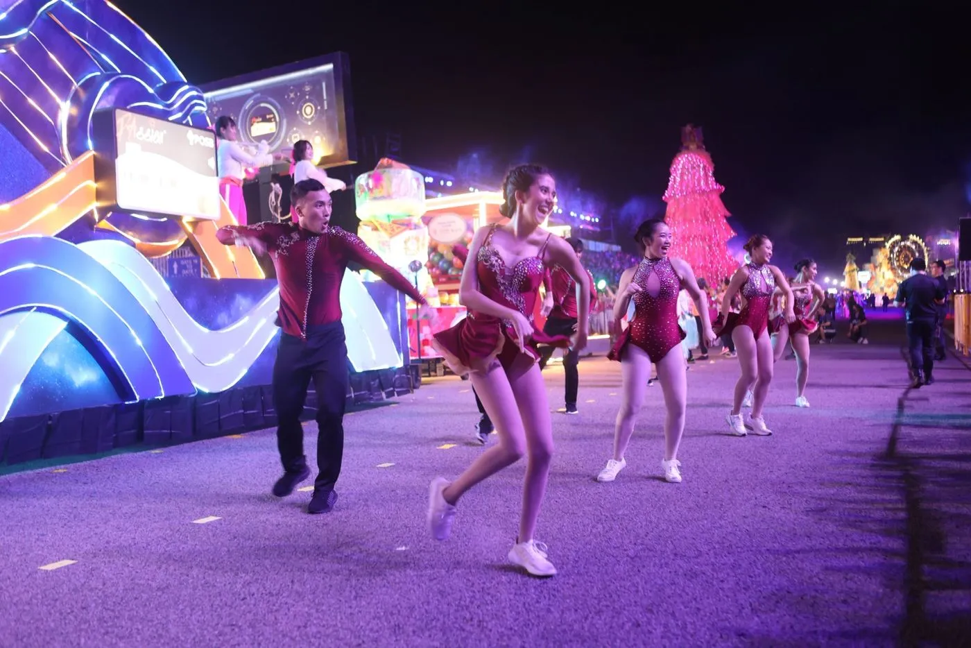Dancers passing an illuminated float during a night parade